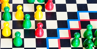 Een zwart-wit speelbord met groene en rode speelstukken erop.