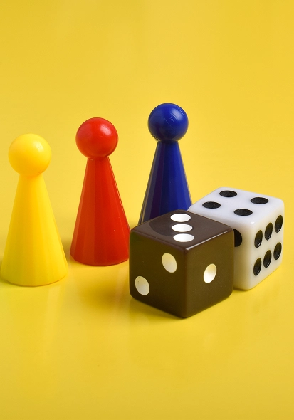 Tegen een felgele achtergrond staan speelfiches en ligt een dobbelsteen.